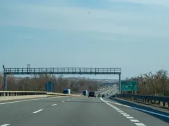 Toll enforcement cameras on the D2 motorway in the Czech Republic heading towards Bratislava and the Slovak border, with distance sign showing Kúty 18 km and Státní hranice 12 km
