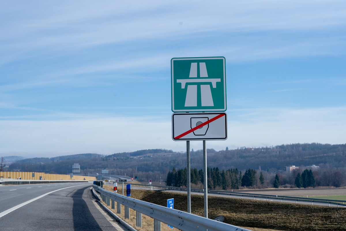 Czech D3 motorway sign with crossed-out e-vignette symbol below the green motorway sign indicating a vignette-free stretch of the D3 motorway, modern noise barriers and open countryside with rolling hills near České Budějovice in South Bohemia, February 2026
