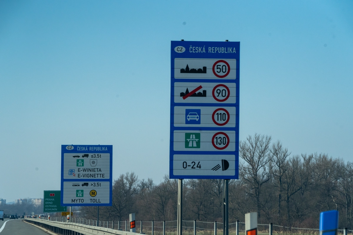Czech Republic border information signs at the Polish crossing showing speed limits (50, 90, 110, 130 km/h) and 0-24h dipped headlights rule, alongside bilingual E-WINIETA / E-VIGNETTE sign for vehicles ≤3.5t and MYTO toll for vehicles >3.5t, direction sign to Praha, Brno and Ostrava visible, February 2026