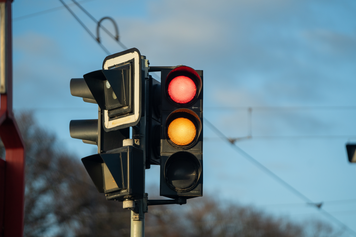 Red and amber traffic light on a Czech Republic local road against blue sky, February 2026