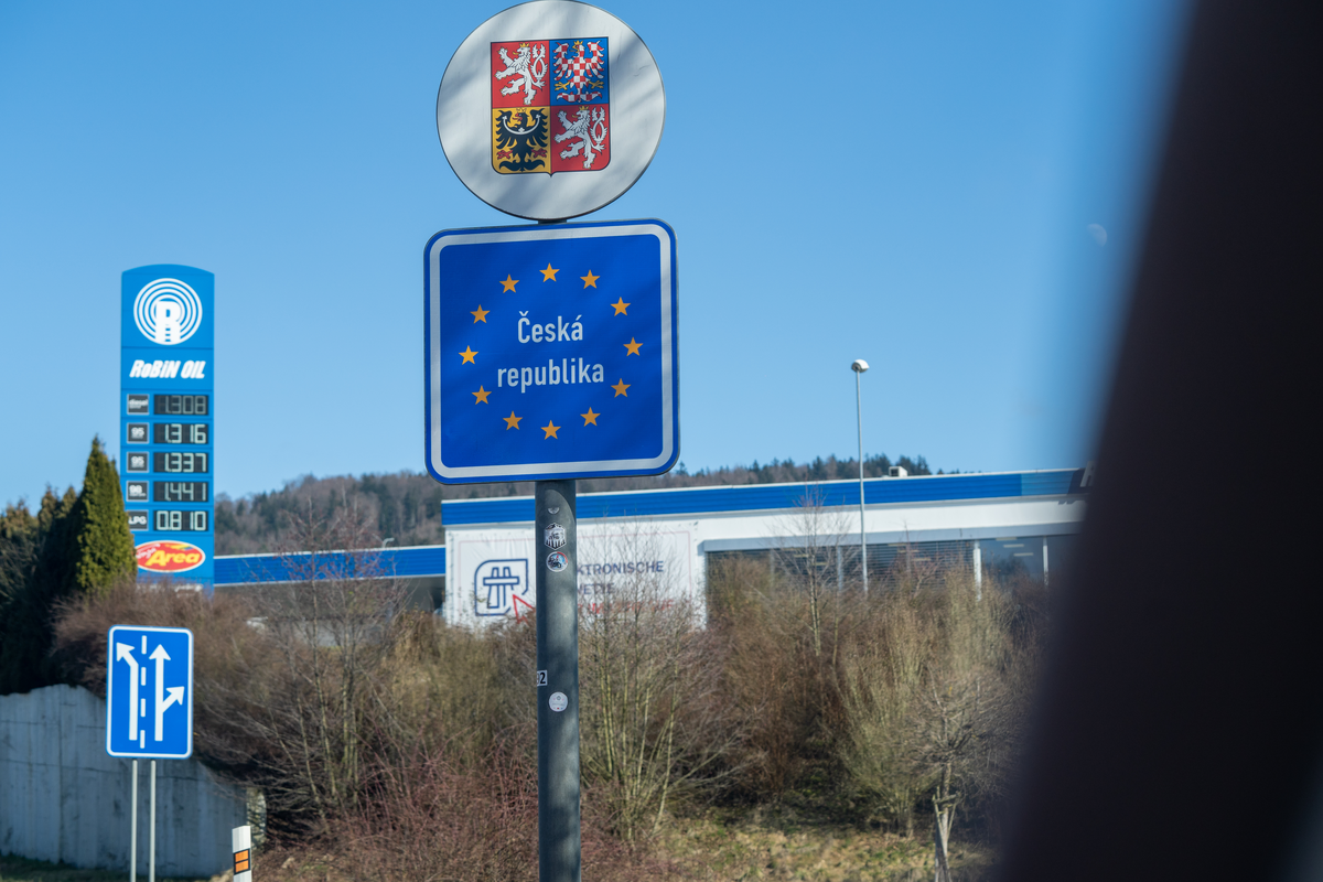 Česká Republika EU entry sign with Czech coat of arms and gold stars on D5 border crossing with Robin Oil fuel station and electronic vignette office visible in background, February 2026