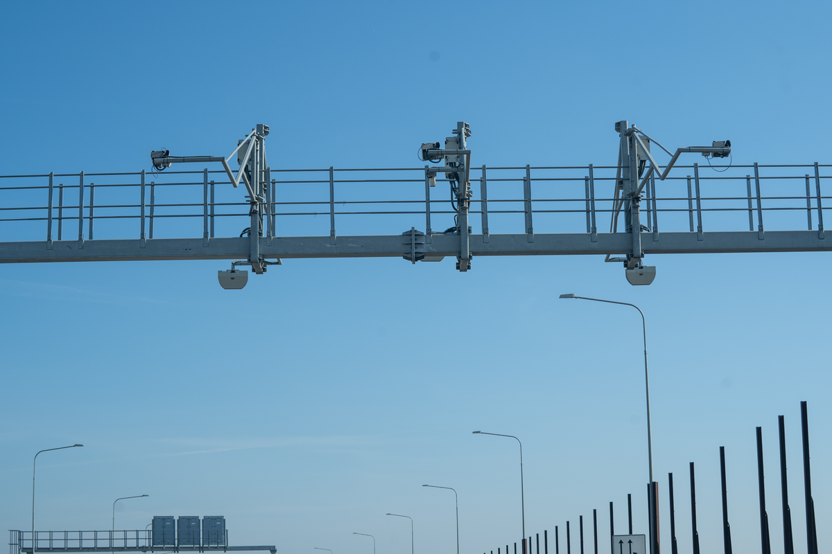 Close-up of Czech vignette enforcement gantry with multiple cameras and sensors mounted on overhead beam on D1 motorway against clear blue sky, February 2026