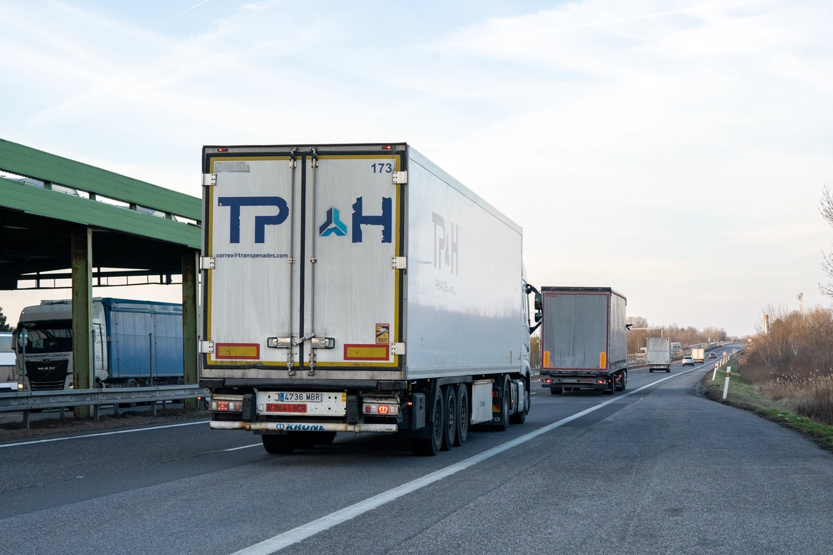 Spanish-registered Krone HGV reefer trailer and other international trucks driving on a Czech motorway near a former border inspection canopy, illustrating MYTO toll obligation for vehicles over 3.5t, February 2026