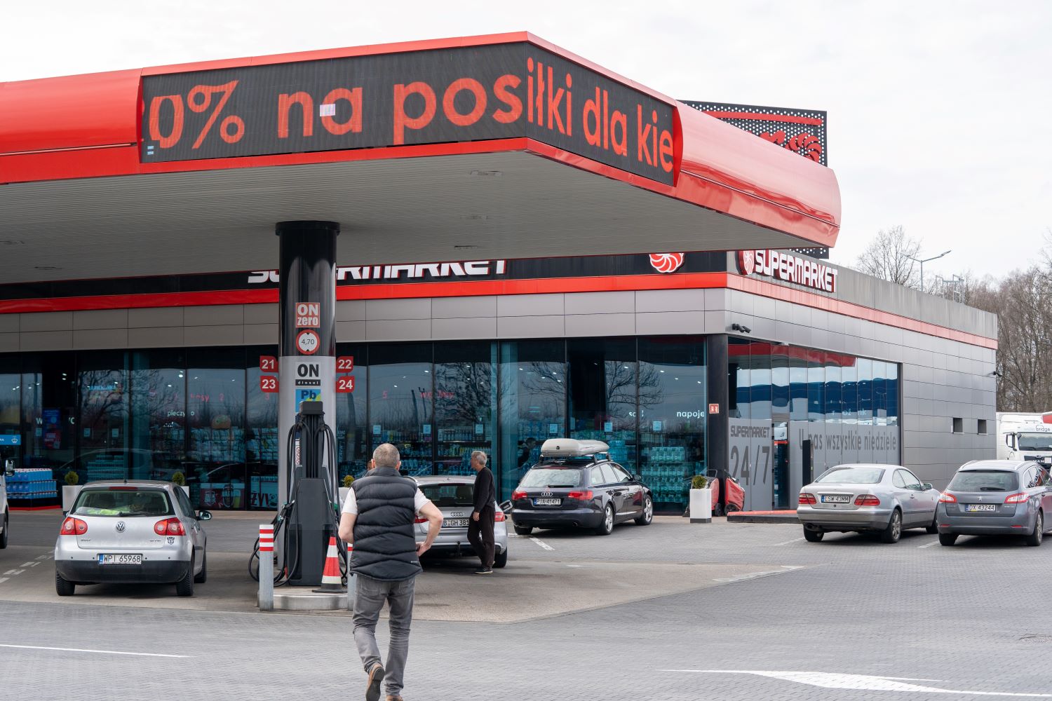 Polish petrol station with a 24/7 supermarket and a scrolling sign offering drivers a meal discount, with Polish and German cars 