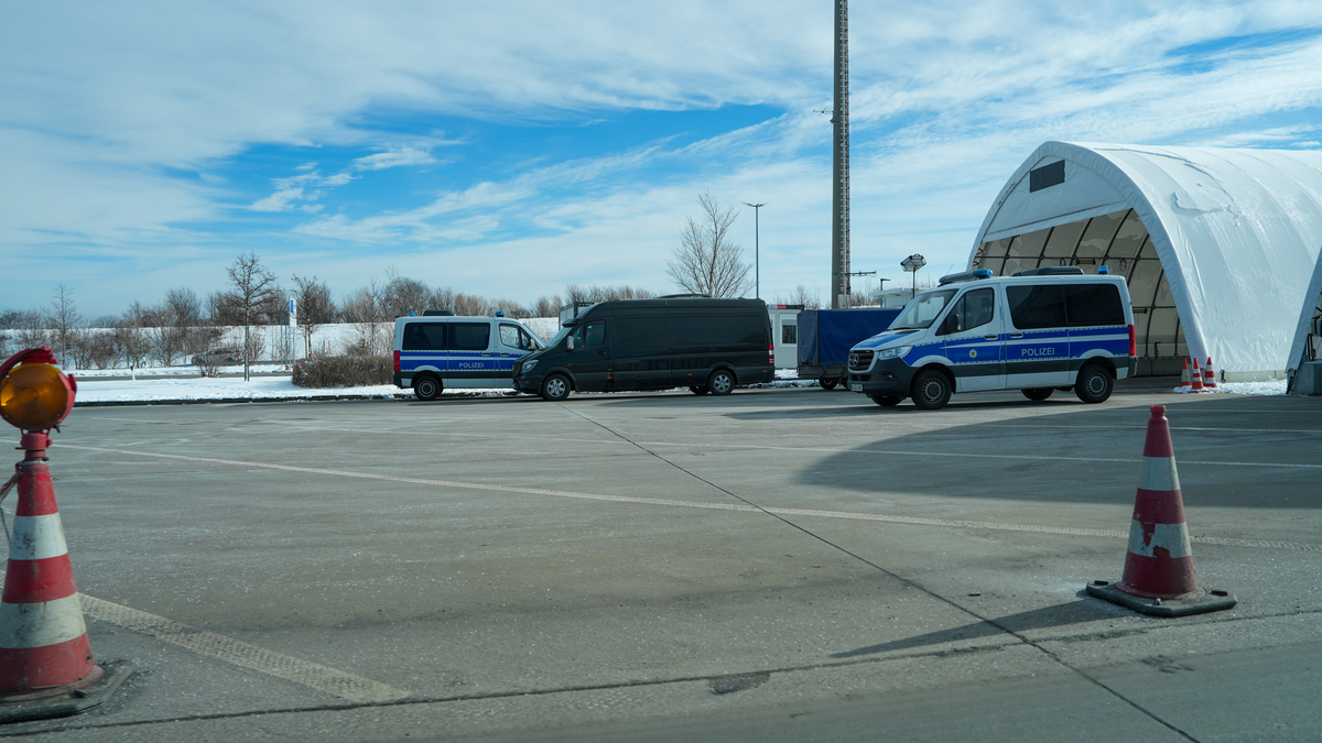 Petrovice–Breitenau border crossing infrastructure on the D8/A17 between Czech Republic and Germany, with two German Polizei Sprinter vans, large white inflatable inspection tent and red-white traffic cones marking the checkpoint lane, snow-dusted winter ground, February 2026