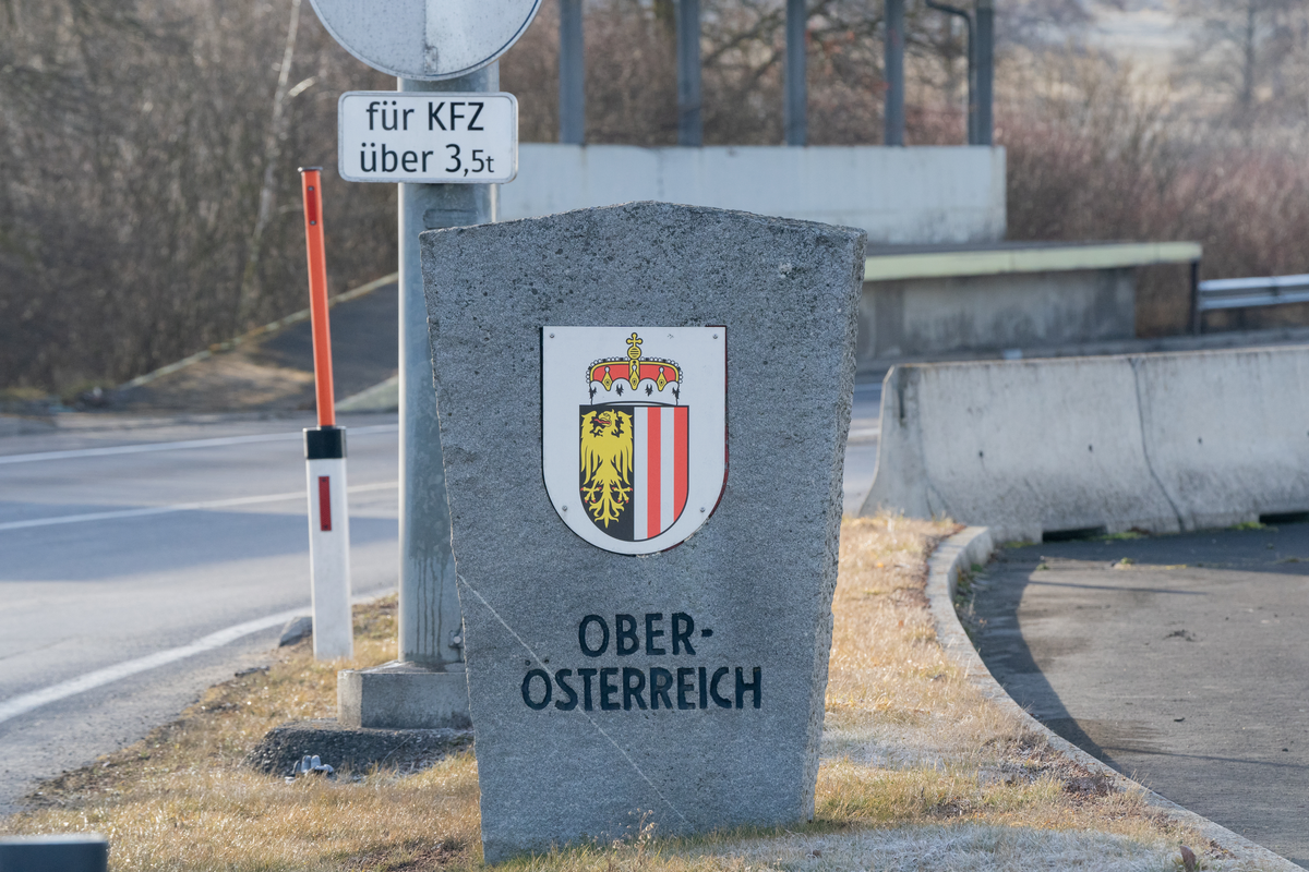 Granite stone border marker with Oberösterreich coat of arms at the Wullowitz–Dolní Dvořiště border crossing between Czech Republic and Austria, with German für KFZ über 3,5t sign indicating the HGV toll rule for vehicles over 3.5 tonnes, on the E55 between Prague and Linz, February 2026